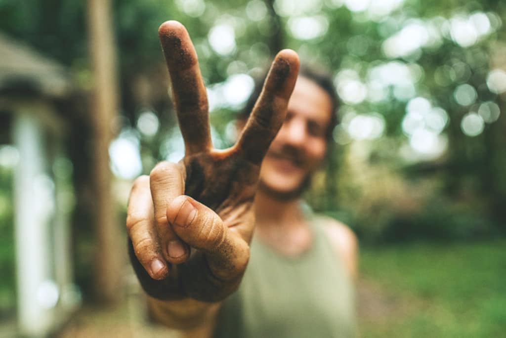 Backpacker qui fait le signe Victoire avec ses doigts après avoir trouvé un job dans le fruit picking en Australie grâce au Guide des Backpackers