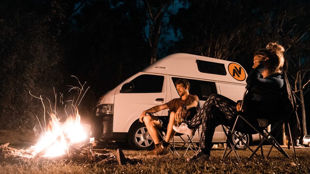 Couple à côté du feu près de leur van qu'ils ont loué en Australie