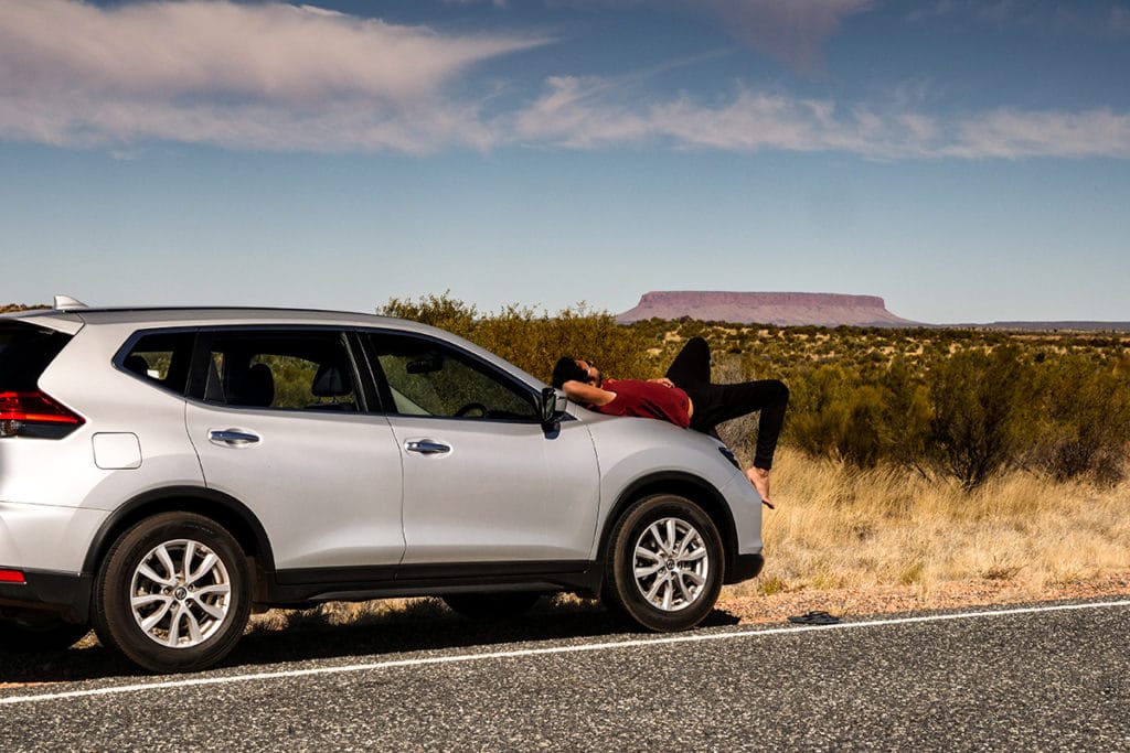 homme allongé sur sa voiture après avoir passé son permis de conduire en Australie