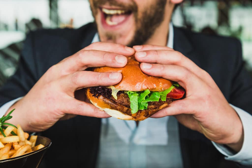 Homme mangeant un Burger livré par Uber Eats en Australie.