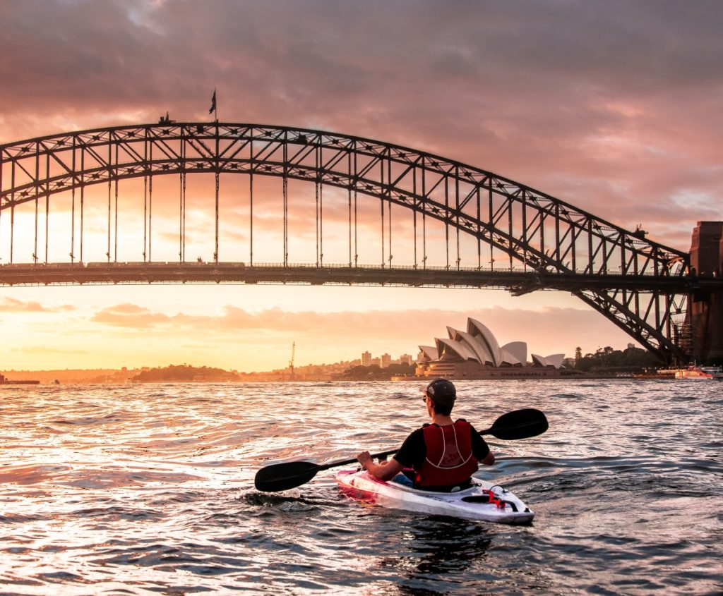 homme en kayak devant le harbour bridge à sydney en australie