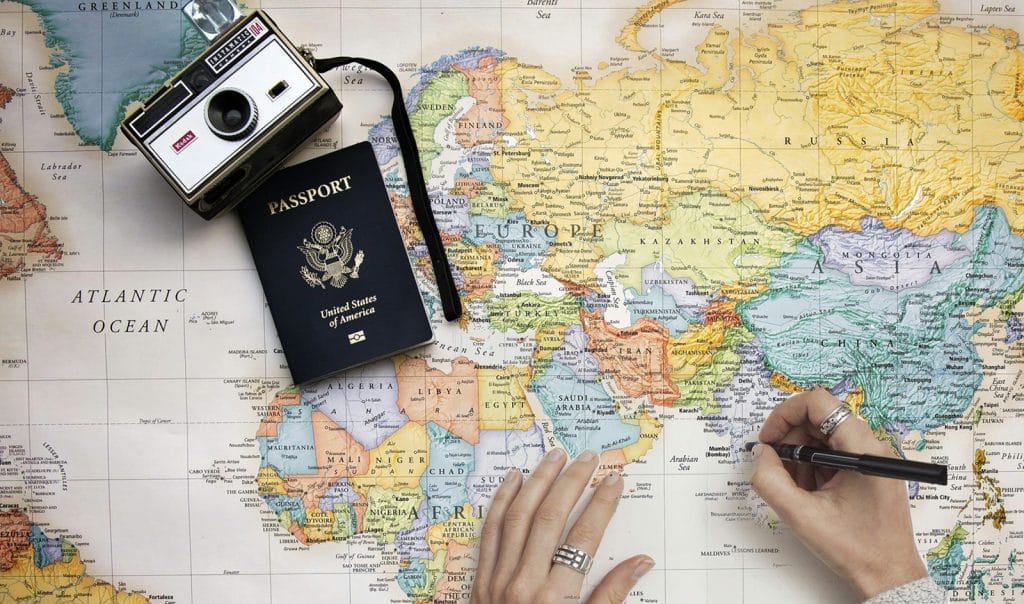 carte du monde avec un passeport et un appareil photo, la personne prépare son tour du monde et se demande quelle assurance santé prendre