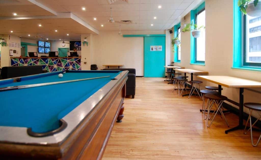 Salon d'une auberge de jeunesse avec billard et table pour prendre le café