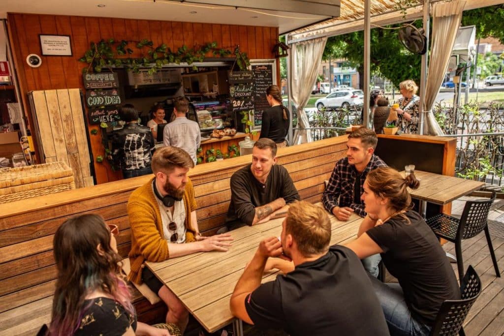 Bar restaurant d'une auberge de jeunesse avec des backpackers qui discutent autour d'une table