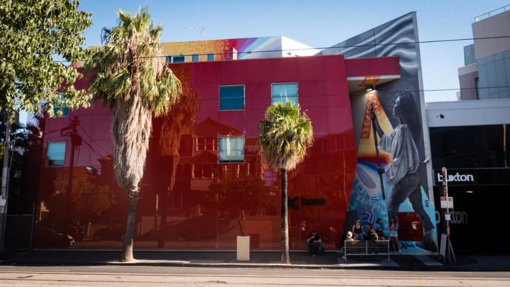 Le Nomads de St Kilda à Melbourne avec des Backpackers qui discutent devant et une grande peinture murale.