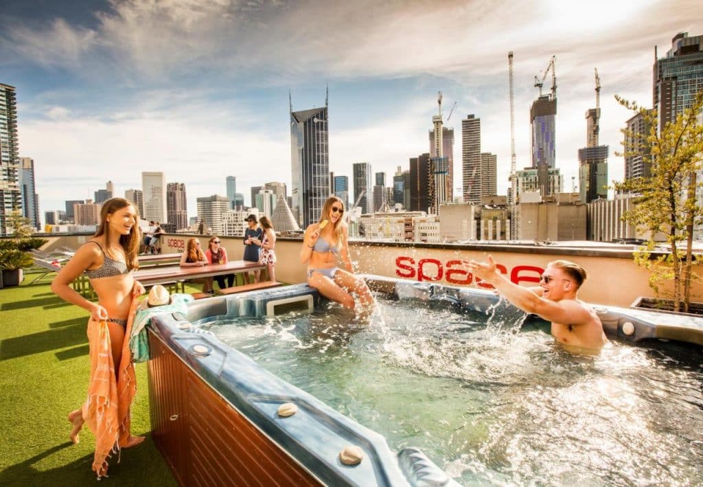 Piscine en extérieur avec jacuzzi sur le rooftop de Space Hotel dans le CBD avec des backpackers qui s'amusent et rient